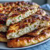 A warm, fluffy Best Easy Garlic Naan Bread brushed with garlicky butter, ready to serve with curry.