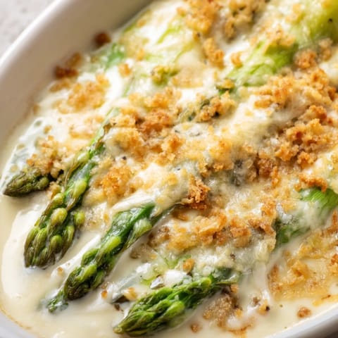 Asparagus Casserole bubbles with melted Gruyère and Parmesan, served hot from the oven alongside a colorful spring salad.
