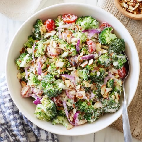 Freshly made Garlic Parmesan Broccoli Salad topped with toasted almonds and parsley, served as a chilled side for summer picnics.  