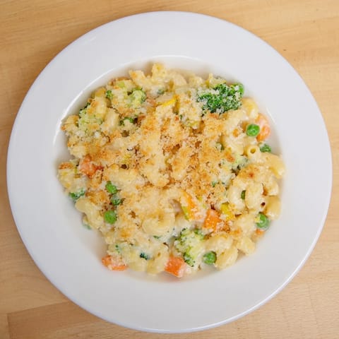 Golden, bubbly Garden Veg Mac and Cheese in a casserole dish, topped with crispy panko and served with a fresh side salad.