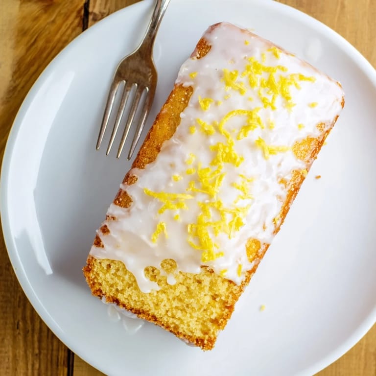 Homemade Lemon Pound Cake cooling on a wire rack, featuring a golden-brown crust and glistening zesty lemon glaze.