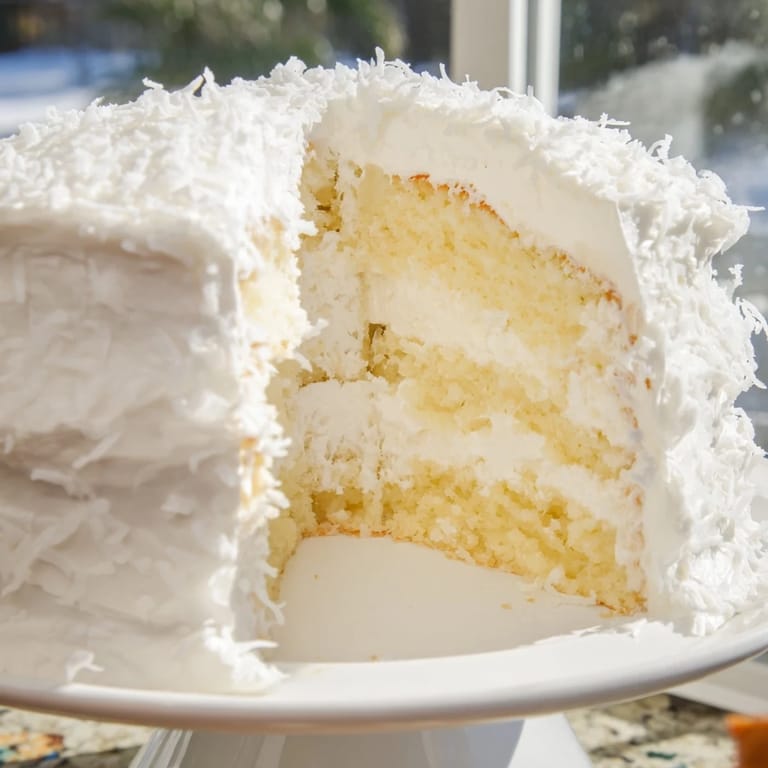 A slice of seven-minute coconut cake is served with a steaming cup of black tea for an afternoon treat.