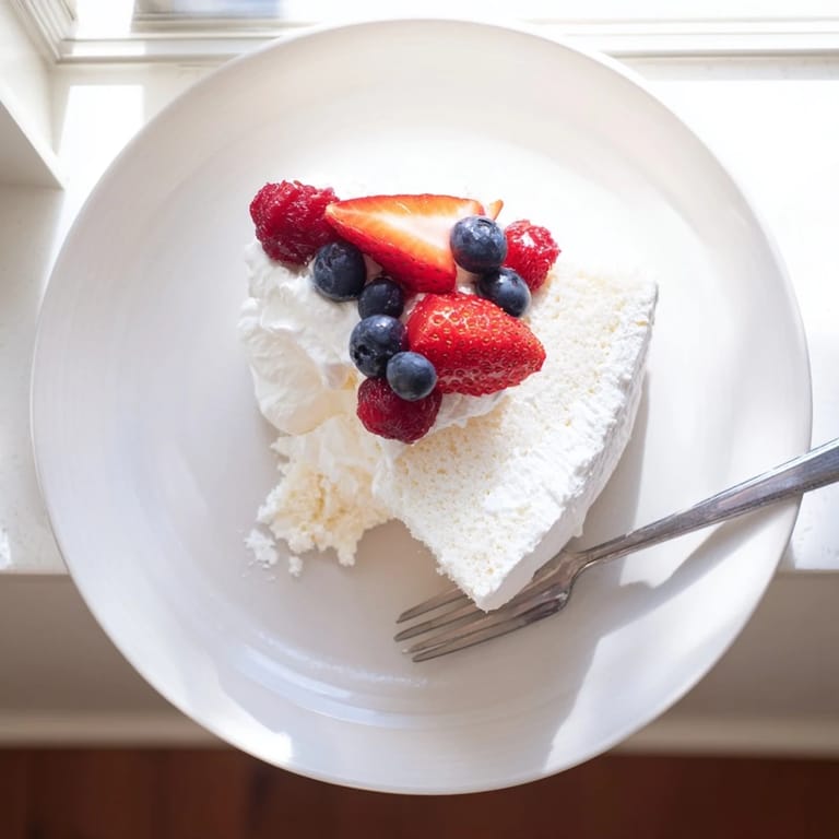 Tall, airy slices of Angel Food Cake on a white plate, revealing the delicate, fluffy crumb texture inside.