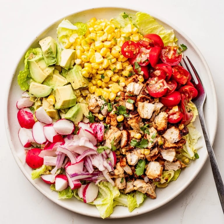 This Roasted Corn & Chicken Chopped Salad showcases charred corn kernels, sliced radishes, and diced avocado tossed in a bright, homemade lime vinaigrette.